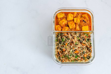 Foto de Comida vegetariana india combinada de arroz frito y mantequilla Paneer Masala en una lonchera Foto de comida de arriba abajo sobre fondo blanco - Imagen libre de derechos