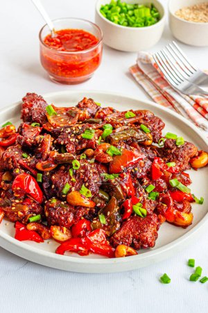Téléchargez les photos : Plat de poulet fusion indo-chinois frit avec sauce chili, garni d'une photo verticale à grand angle d'échallion frais - en image libre de droit