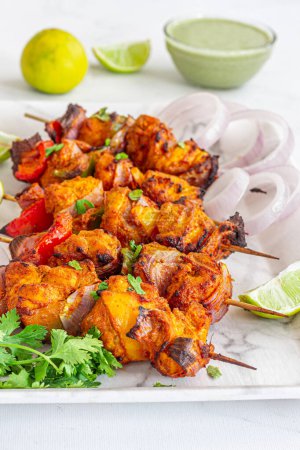 Indisches Huhn Tikka Kebab mit grünem Chutney, Zwiebeln und Koriander Großaufnahme Foto