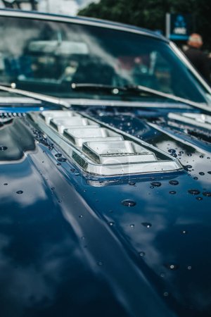 Támesis, Nueva Zelanda, 24 de noviembre de 2022, Beach Hop Car Rally: Restaurado Vintage coche azul medianoche con gotas de lluvia y reflejos de las nubes en el capó.