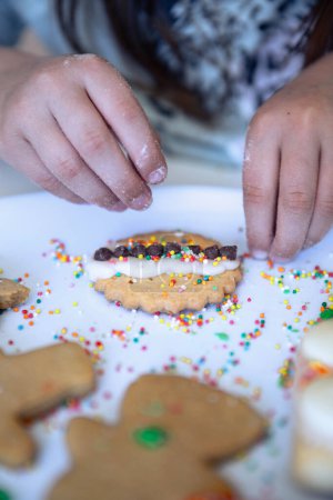 Photo for Little hands decorating a Christmas cookie with hundreds and thousands and festive happiness and love. - Royalty Free Image