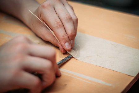 Primer plano de un adolescente usando herramientas que trabajan con sus manos aprendiendo un oficio de carpintería de carpintería.