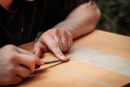Nahaufnahme eines halbwüchsigen Jungen, der mit Werkzeugen arbeitet, die mit seinen Händen das Tischlerhandwerk erlernen.