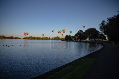 Photo for Hamilton, New Zealand, 14 March 2023: Balloons over Waikato at dawn, view from across the lake - Royalty Free Image