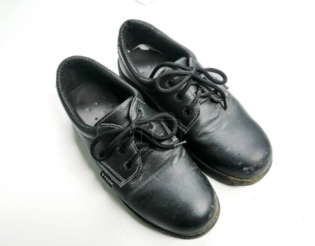 Vieilles chaussures de sécurité noires qui ont été utilisées beaucoup et sont sales depuis longtemps. Fond blanc isolé