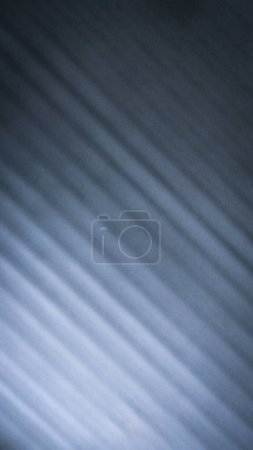The photograph has a blurry, gray, black background. The surface is rough with uneven diagonal lines. Gradient and brightnes