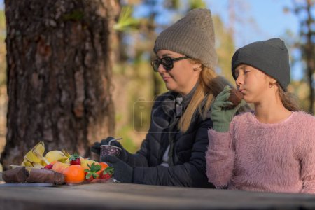Mädchen riecht einen leckeren Kuchen, den ihre Mutter ihr gemacht hat und genießt den Sonnenuntergang auf einem Campingplatz gesundes Leben Kontakt mit der Natur Winterzeit und Muttertag