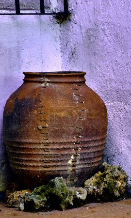 Old jar with stones around it and white background.