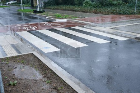 Téléchargez les photos : Piste cyclable traverse la route automobile sous la pluie battante - en image libre de droit