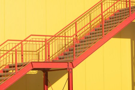 red metal outdoor stairway in front of yellow wall
