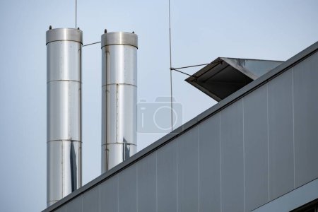 large stainless steel chimneys on the roof of an industrial building