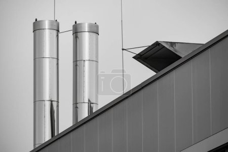 große Edelstahlschornsteine auf dem Dach eines Industriegebäudes