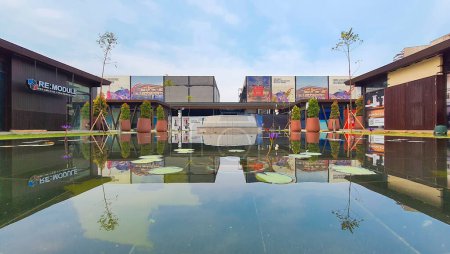 Téléchargez les photos : Jakarta 01 Nov 2023 : plan frontal de banc en béton et pot de plantation devant une piscine réfléchissante avec nénuphars. bâtiments en arrière-plan. réflexion symétrique Indonésie Design District PIK 2 - en image libre de droit