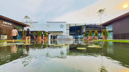 Téléchargez les photos : Jakarta 01 Nov 2023 : plan frontal de banc en béton et pot de plantation devant une piscine réfléchissante avec nénuphars. bâtiments en arrière-plan. réflexion symétrique Indonésie Design District PIK 2 - en image libre de droit