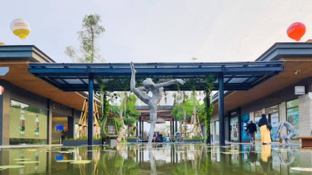 Téléchargez les photos : Jakarta 01 Nov 2023 : Plan frontal d'une œuvre d'art en acier de danseur de ballet flottant sur un étang réfléchissant. nénuphars, plantes tropicales. ballons, ciel couchant. Indonésie Design District centre commercial de bande extérieure - en image libre de droit