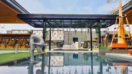 Téléchargez les photos : Jakarta 01 Nov 2023 : prise de vue frontale d'un étang réfléchissant bleu avec une sculpture en acier et une verrière en acier. Indonésie Design District PIK2 - en image libre de droit