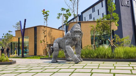 Téléchargez les photos : Jakarta Nov 01 2023 : Statue de gorille en chrome géant en Indonésie Design District PIK 2. une statue métallique devant un pop-up store jaune et un joli paysage tropical - en image libre de droit
