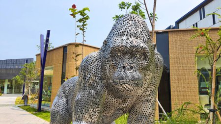 Téléchargez les photos : Jakarta Nov 01 2023 : Statue de gorille en chrome géant en Indonésie Design District PIK 2. une statue métallique devant un pop-up store jaune et un joli paysage tropical - en image libre de droit