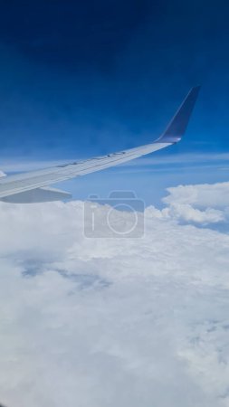 Wing of an airplane with a bluetip with beautiful blue sky and white cloud as background