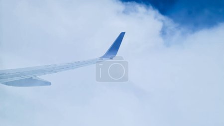 Wing of an airplane with a bluetip with beautiful blue sky and white cloud as background