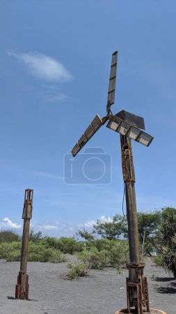 eine alte Windmühle auf einem heißen Sandfeld mit klarem blauen Himmel