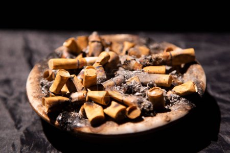 Photo for Pile of cigarette butts in the ashtray with black background - Royalty Free Image