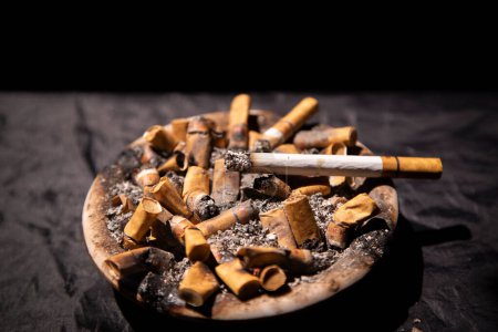 Photo for High angle view of cigarettes burning in ashtray full of cigarette butts - Royalty Free Image