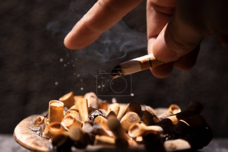 Photo for Throwing cigarette ash with a finger on the dirty ashtrays full of butts - Royalty Free Image