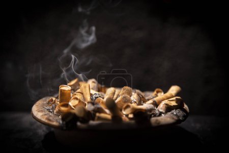 Photo for Smoke came out of the pile of cigarette butts in the ashtray - Royalty Free Image