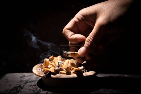 Photo for Throw cigarette ashes in the ashtray with black background - Royalty Free Image