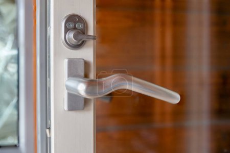 Metal Door handle and lock on a glass door with white frame.