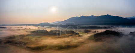 Sunset Panorama with drone at the Bavarian Alps. Mist and fog at the ground. High quality photo
