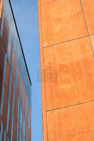 Fond de façades architecturales orange et marron où la verticalité prédomine avec le ciel au milieu.