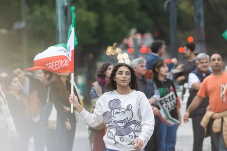 Photo for 10-29-2022 LISBON, PORTUGAL: RALLY DEDICATED TO MAHSA AMINI - young woman holding iranian flag. Mid shot - Royalty Free Image