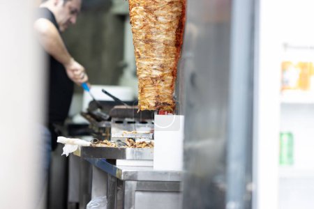 Téléchargez les photos : Un homme cuisine shawarma - la viande est frite sur une valve. À mi-coup - en image libre de droit