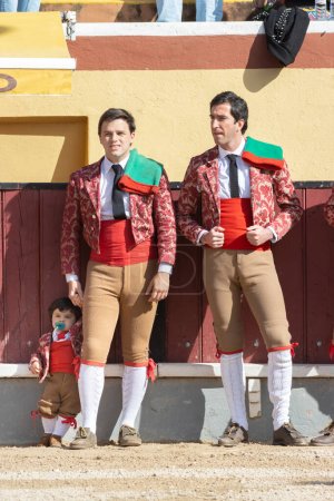 Photo for March 26, 2023 Lisbon, Portugal: Tourada - bullfighters standing on arena and a baby boy wearing same costume with them. Mid shot - Royalty Free Image