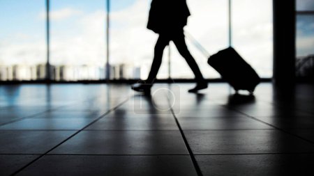 Téléchargez les photos : Voyageur à l'aéroport marchant vers les départs devant la fenêtre, couleurs bleues - en image libre de droit