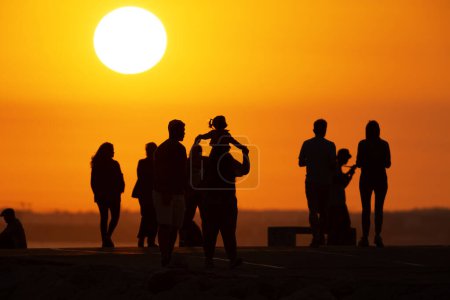 Photo for Black silhouettes of people walking on the hill at sunset. Mid shot - Royalty Free Image