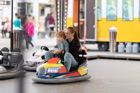 Photo for Angry mom scolds her son sitting in the dodgem. Mid shot - Royalty Free Image