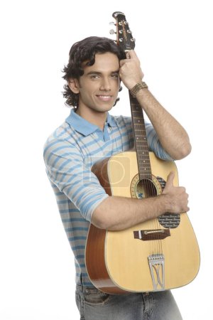 Photo for Teenage boy holding guitar close to him - Royalty Free Image