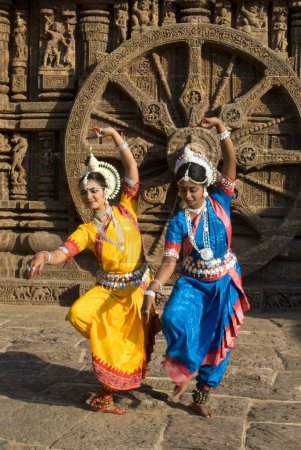 Foto de Bailarines de Odissi posan representan mitos indios como el Ramayana frente al icónico carruaje del sol en el complejo del templo del sol de la herencia de mundo en Konarak, Orissa, India - Imagen libre de derechos