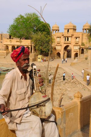 Photo for Folk musician playing musical instrument at Gadsisar Gadisar lake , Jaisalmer , Rajasthan , India - Royalty Free Image