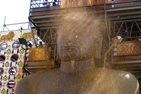 Photo for Jain Devotees Pouring Turmeric Water on forehead of 58.8 feet monolithic Statue of jain saint Gomateshwara in Mahamastakabhisheka on Vindhyagiri hill, Shravanabelagola, Karnataka, India - Royalty Free Image