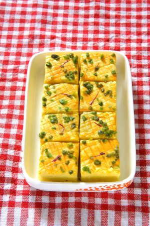 Photo for Indian sweet , sandesh bengali mithai garnish with pistachio and saffron served in container on cloth - Royalty Free Image