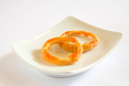 Téléchargez les photos : Cuisine indienne, entrées fast-food Kandy Bhaji beignets d'oignons croustillants anneaux servis dans un plat sur fond blanc - en image libre de droit