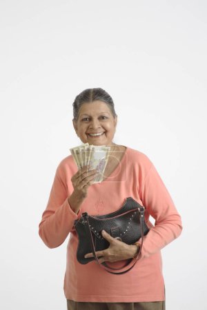Alte Dame mit fünf Scheinen zu je 500 Rupien in der einen Hand und einer Handtasche in der anderen 
