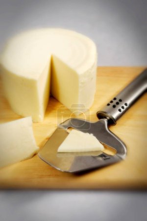 Foto de Cosas de cocina, queso con cortador sobre tabla de madera - Imagen libre de derechos