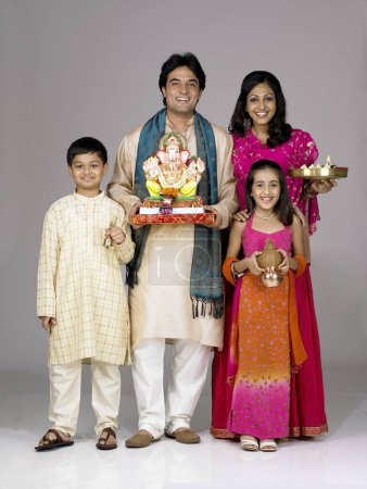 Téléchargez les photos : Famille indienne sud-asiatique avec père mère fils et fille tenant la statue du seigneur Ganesha et Kalash Aarti thali - en image libre de droit