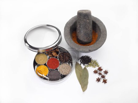 Different types of spices in bowls in stainless steel box with old stone grinder