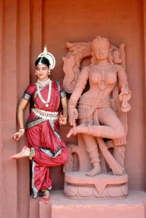 Photo for Woman performing classical traditional Odissi dance at statue on stage - Royalty Free Image